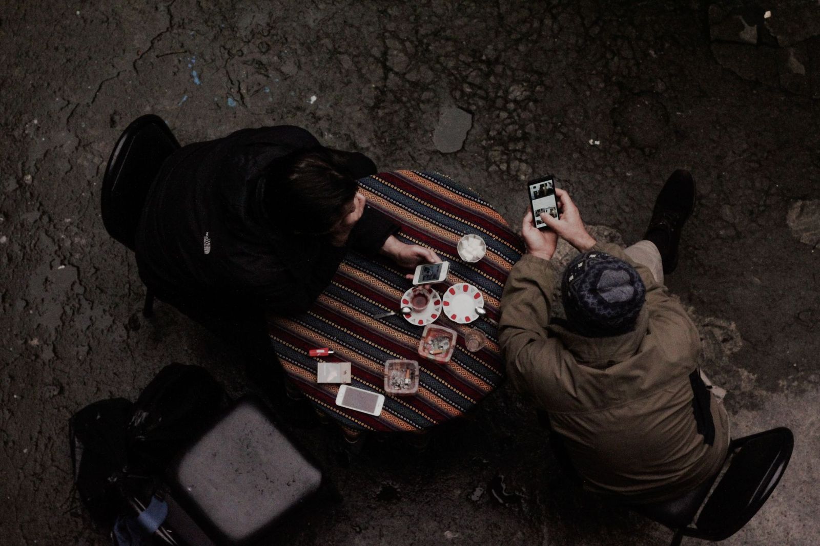 a cafe table with two cups and a phone face down between them || cafe table with two cups and phone face down between them