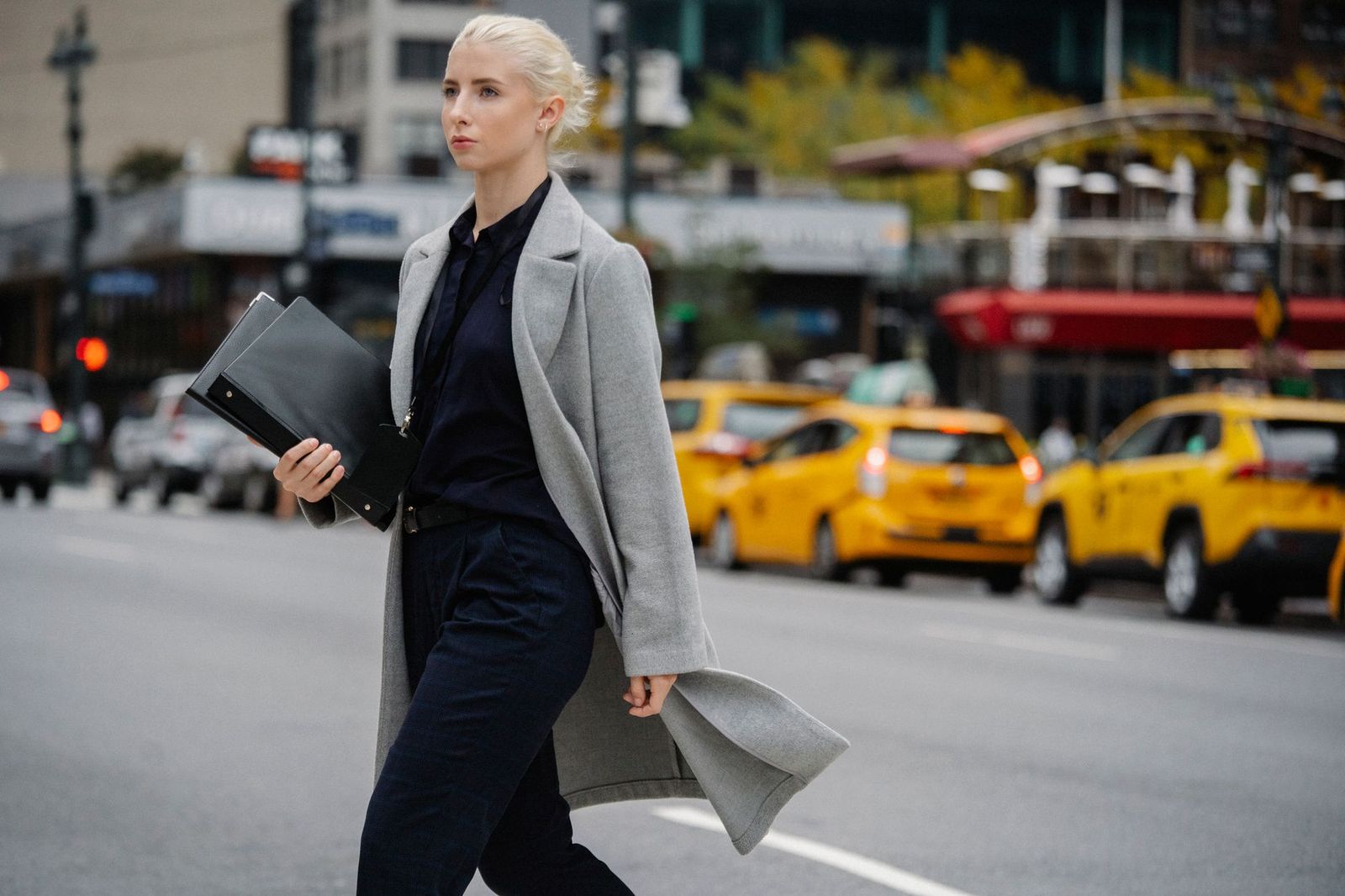 a woman in her mid-thirties walking outside in daylight in a coat, looking forward || woman her mid thirties walking outside coat looking forward