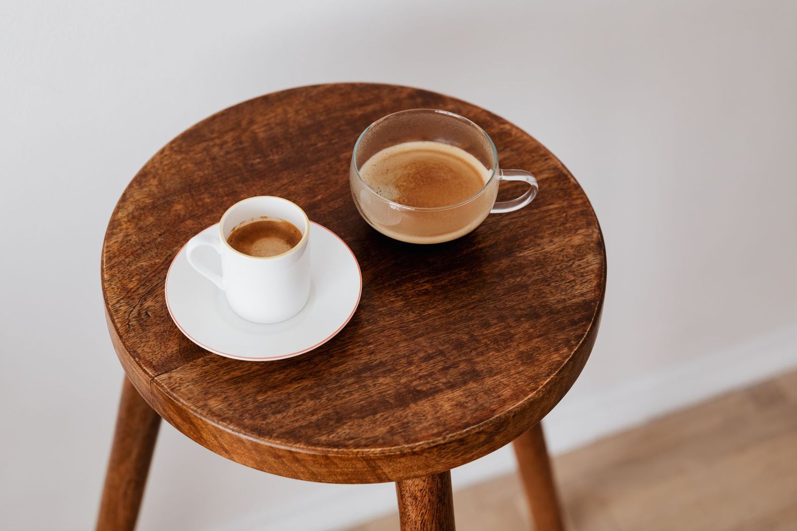 two coffee cups on a table between two empty chairs, daylight || two coffee cups table between two empty chairs