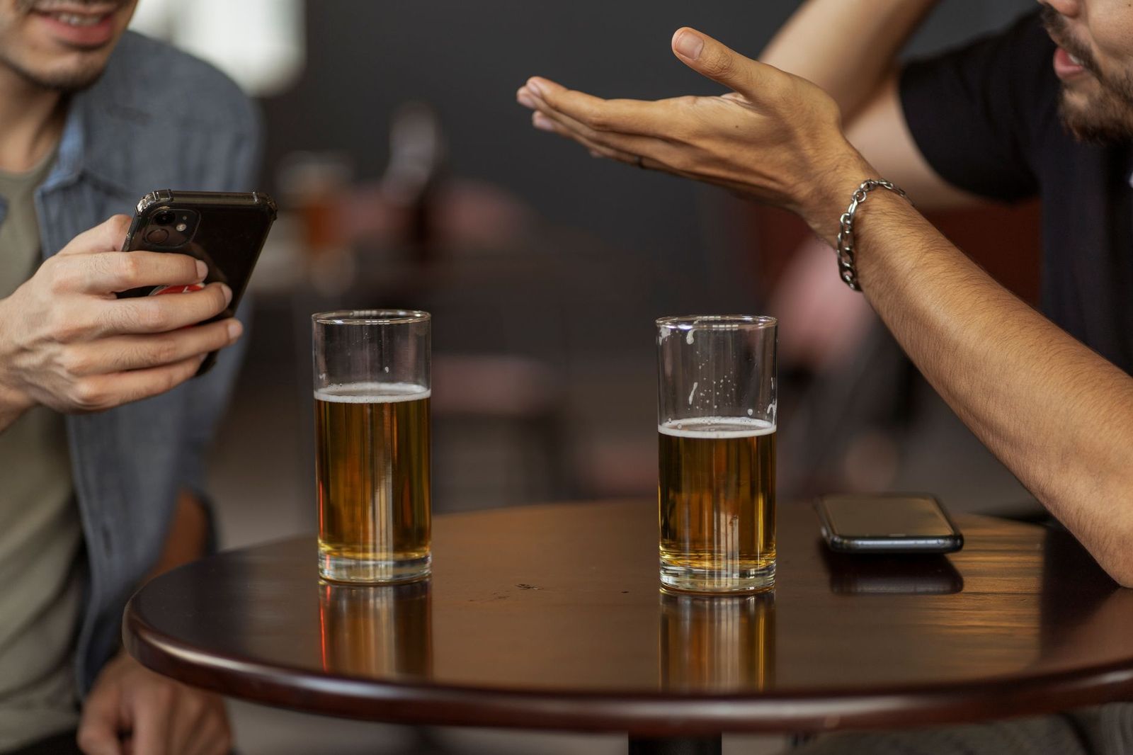 two people in their forties at a bar with exactly one drink each, coats still on, no phones on the table || two people their forties bar with exactly one drink each coats still phones the table thirties
