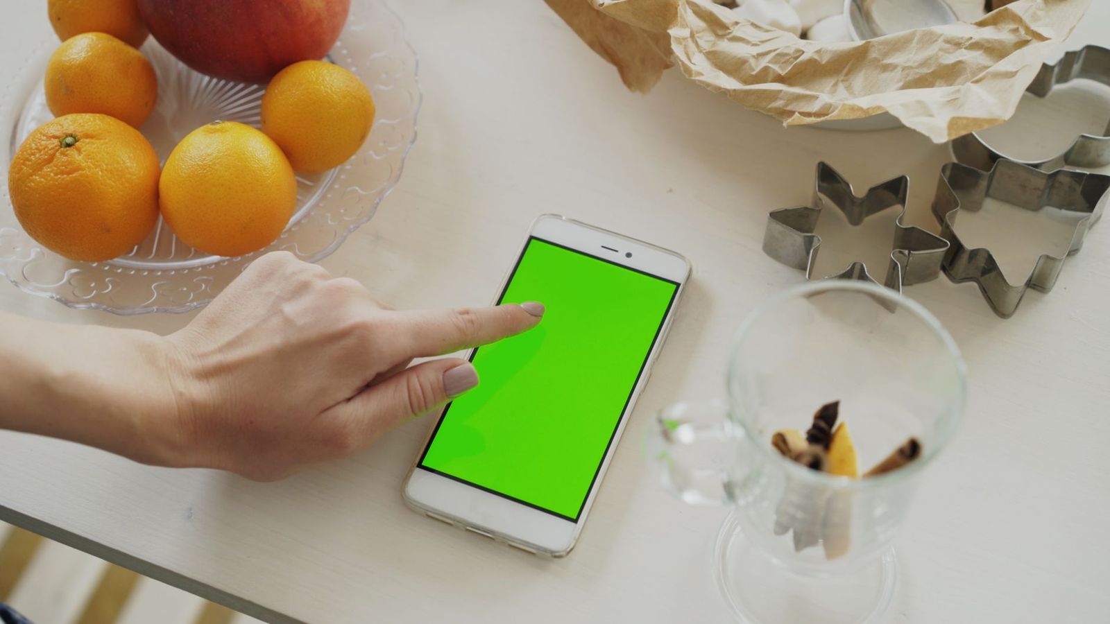 woman around kitchen counter phone face her hand glass water nearby looking the screen one else frame thirties