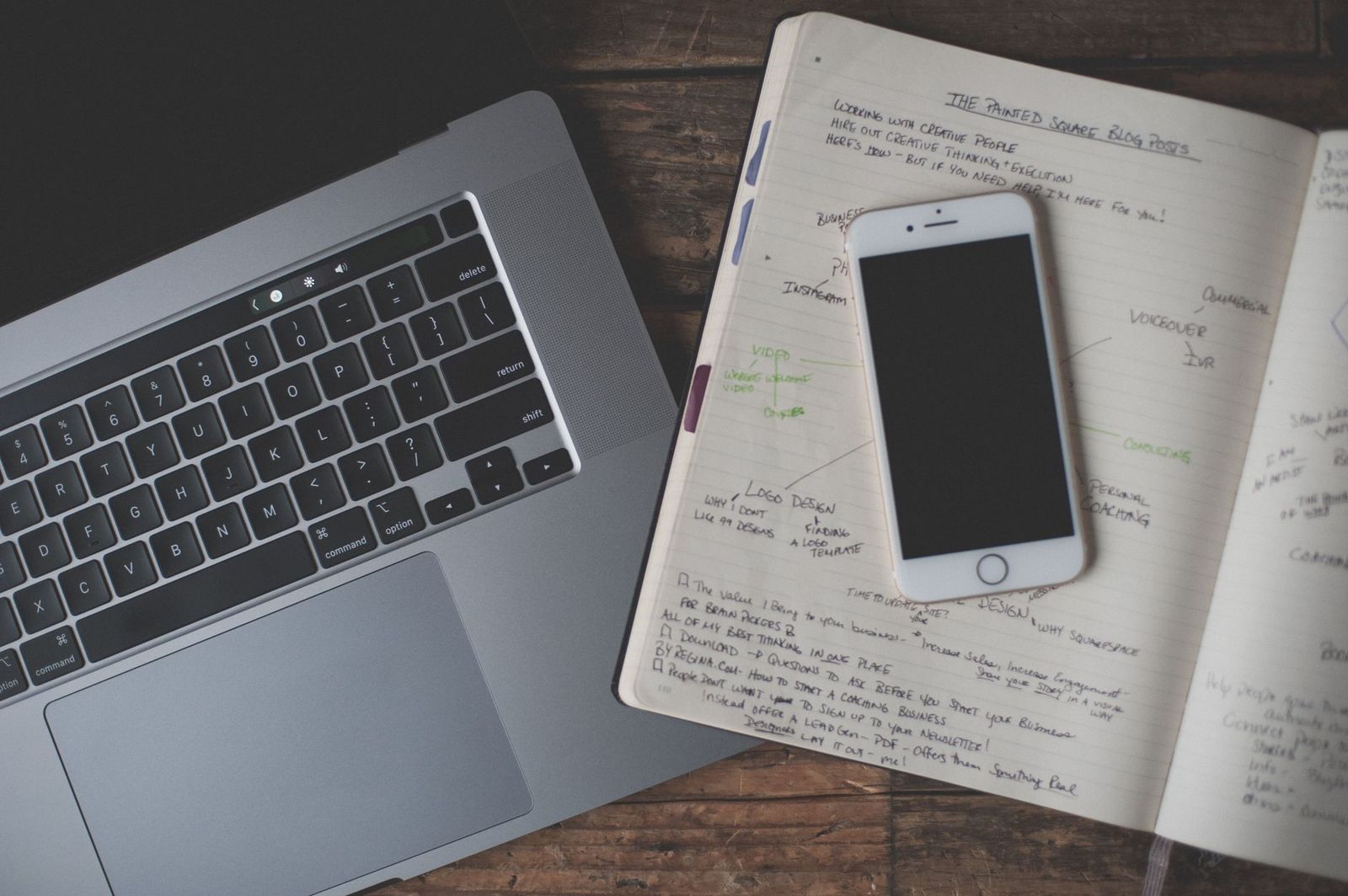 an open notebook on a bedside table with one handwritten sentence, phone face-down beside it || open notebook bedside table with one handwritten sentence phone face down beside