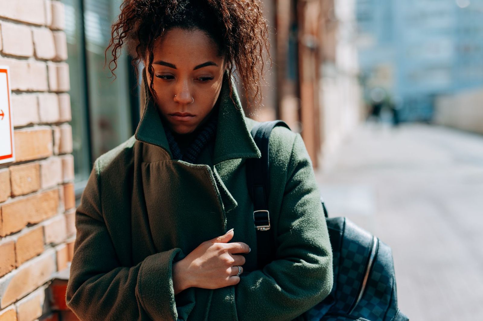a woman in her late thirties walking outside on a sidewalk in daylight, coat on, moving forward alone || woman her late thirties walking outside sidewalk coat moving forward alone