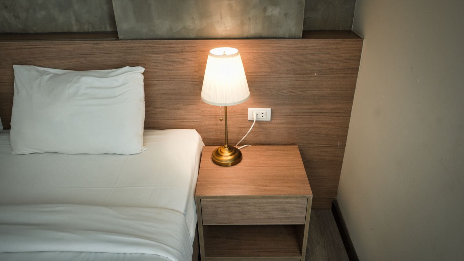 A lamp on a wooden nightstand in a cozy bedroom