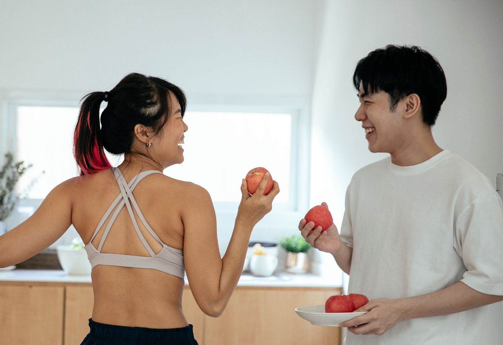 a couple in their forties standing at a kitchen counter in the evening, facing each other mid-conversation; initiation relocated outside the bedroom. || couple their forties standing kitchen counter the facing each other mid conversation initiation relocated outside the bedroom thirties