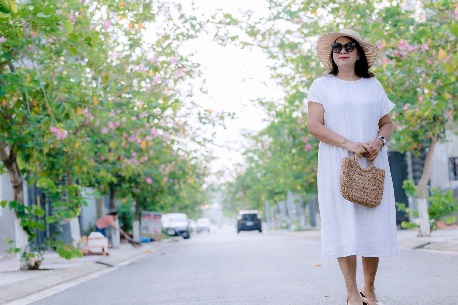 a woman around 40 walking outside in daylight, hands free, phone in her pocket, tree-lined sidewalk || woman around walking outside hands free phone her pocket tree lined sidewalk thirties