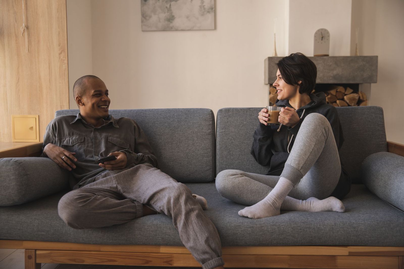 couple their thirties sitting close couch home talking one them smiling mid sentence the other leaning not staged pose