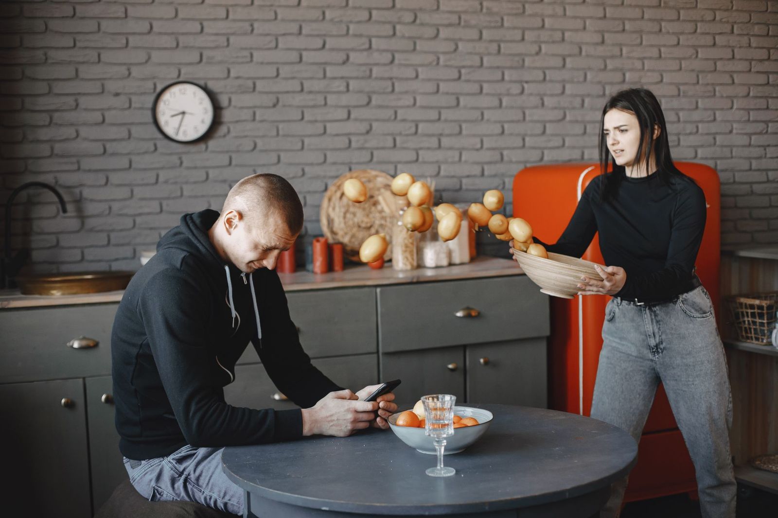 A couple sitting apart at a kitchen island at night, tense