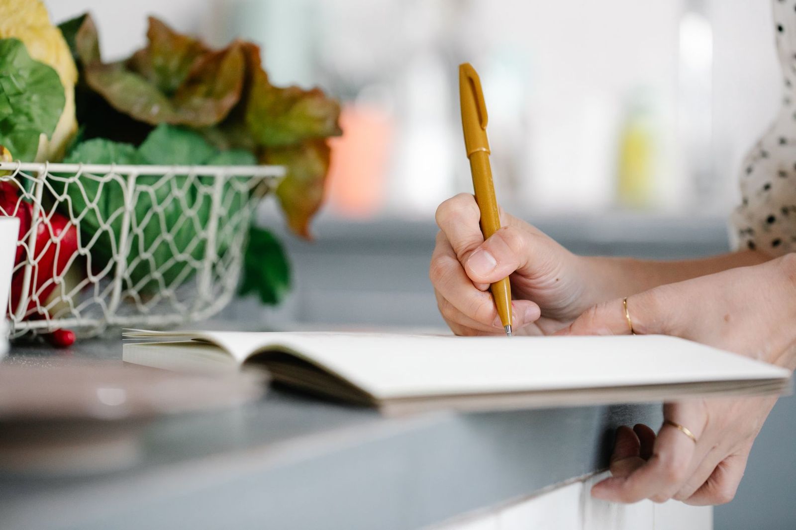 A woman writing in a notebook at a kitchen table in morning light
