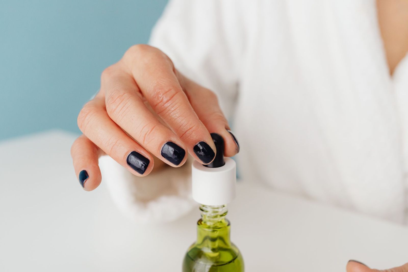 a clean finger with trimmed nails applying water-based lube to a small tube, or a hand holding a bottle || clean finger with trimmed nails applying water based lube tube hand holding bottle