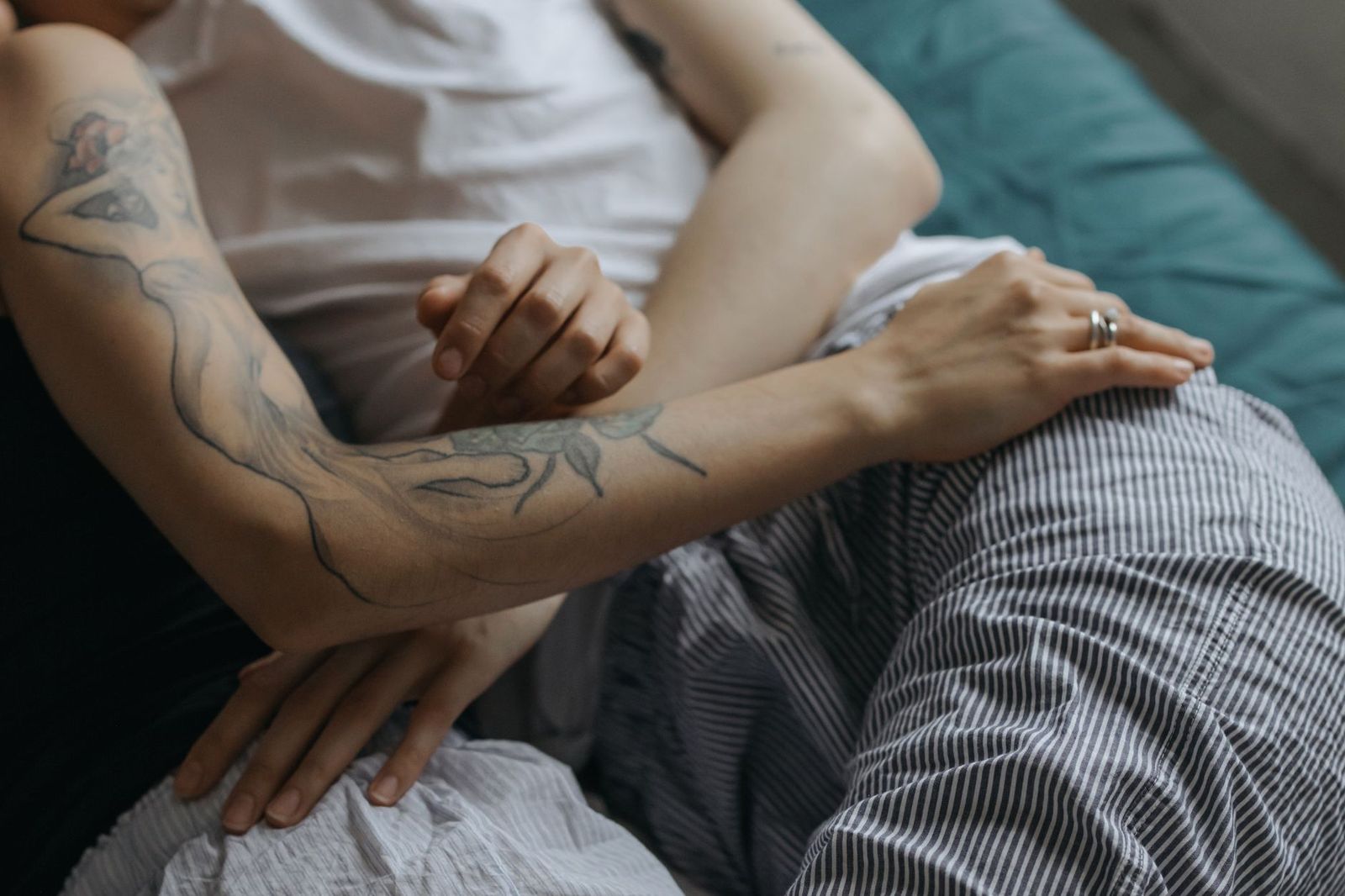 pregnant woman her thirties lying her side bed partner's hand her shoulder both pajamas light but not explicit sec close hands placing pillow under woman's hip bed sec woman bathrobe sitting the edge bed holding bottle lube looking expression