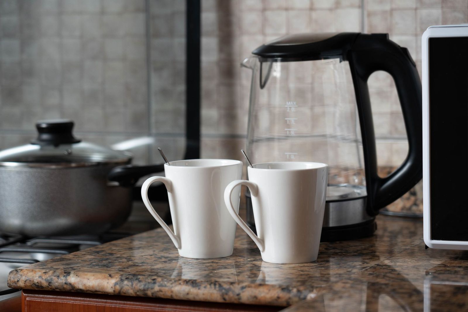 two coffee mugs and a phone face down on a kitchen counter in daylight, no people || two coffee mugs and phone face down kitchen counter people thirties