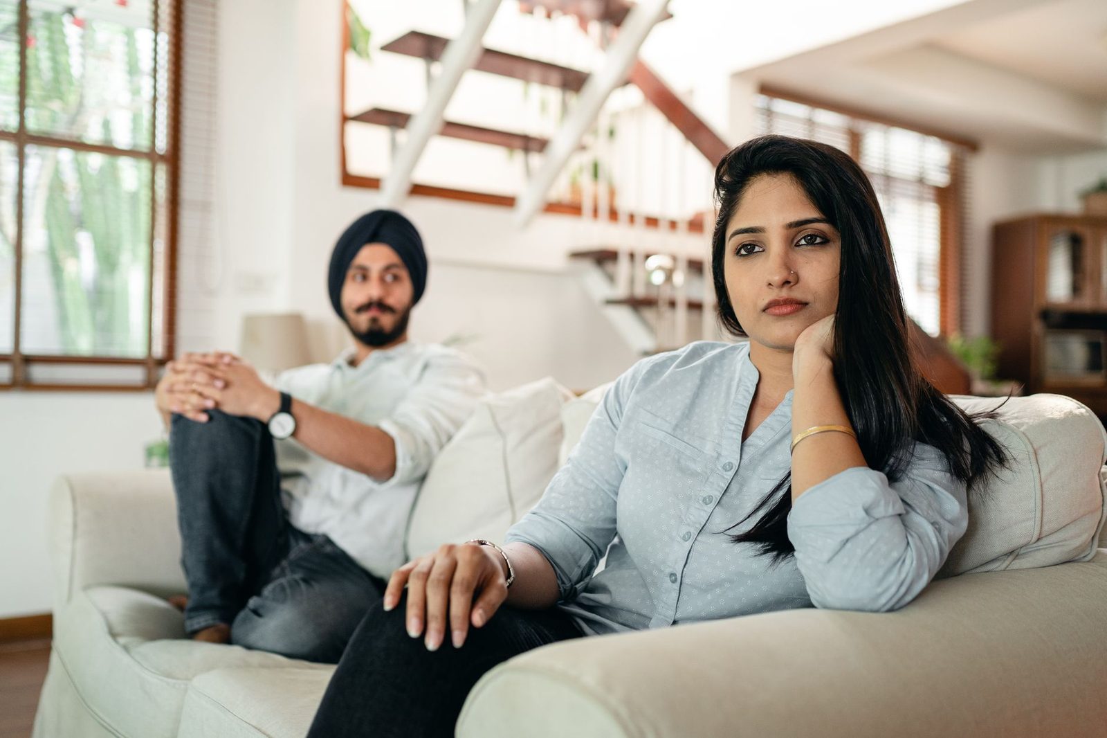 Two people sitting apart on a sofa, neither one talking