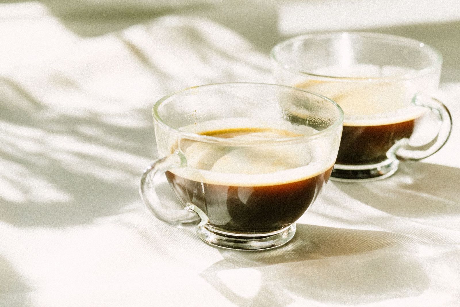 Two cups of coffee on a sunlit table